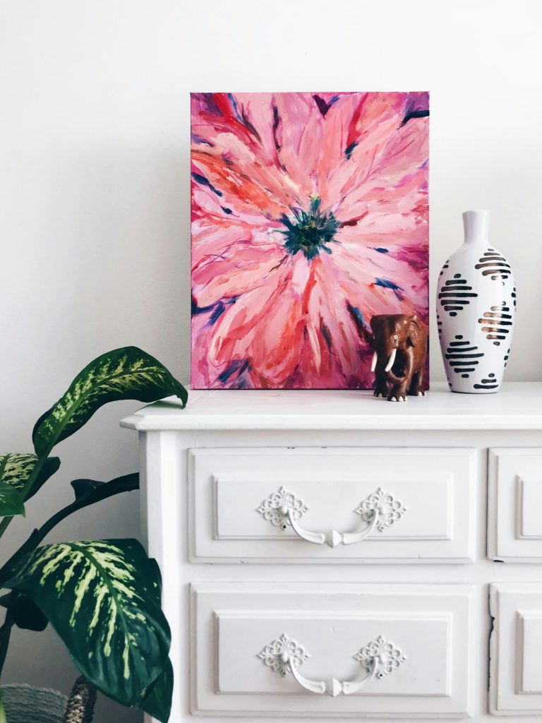 Pink flower artwork with decor on dresser