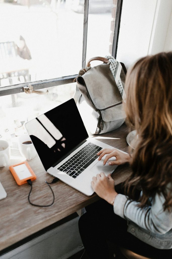 Person using a laptop with orange hard drive