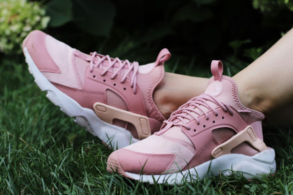 Pink athletic shoes resting on green grass